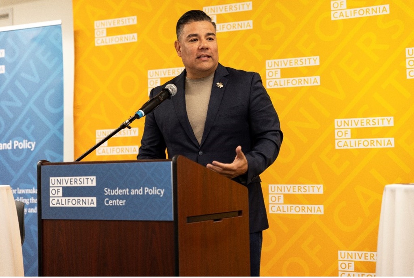 Speaker at a podium with a yellow banner in the background.
